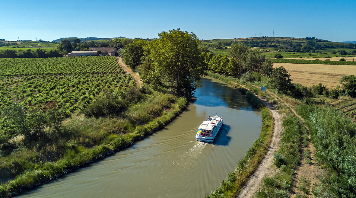 Aerial top view of boat in Canal surrounded by fields